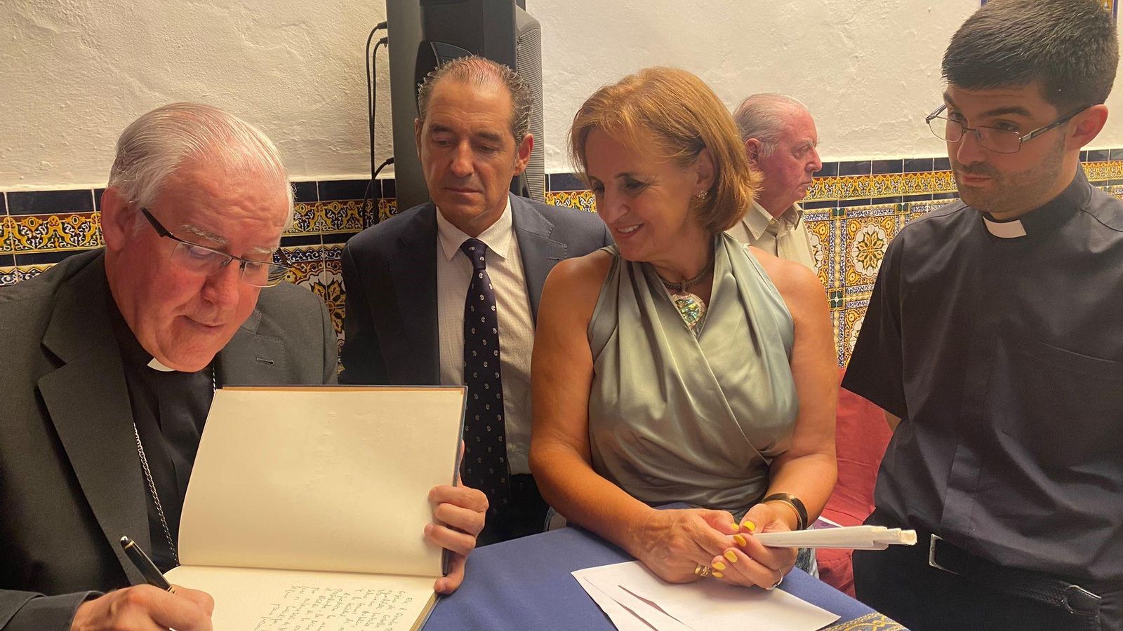Monseñor Saiz firma en el libro de visitas del Casino de Cazalla en presencia de presidente de la entidad, Antonio Jesús Rosendo; la secretaria, Pilar María Roncero; y el párroco de la localidad, Francisco José Gordón.