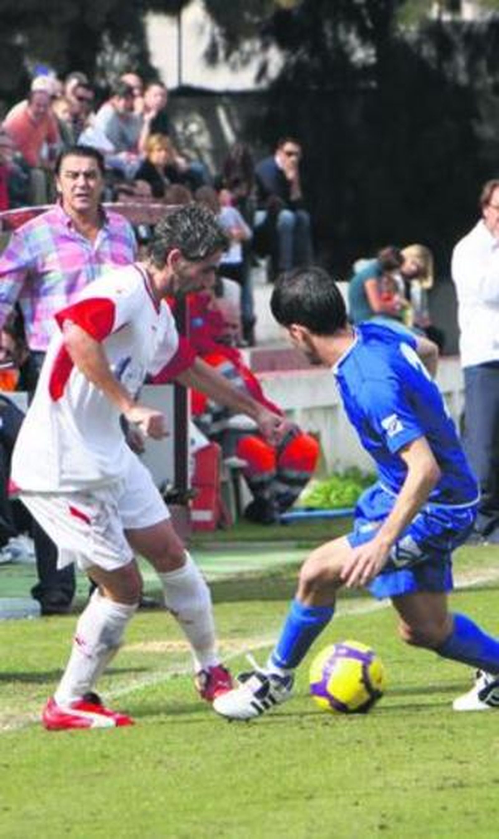 Javi Muñoz regatea a un rival ante la atenta mirada de Bolli.
