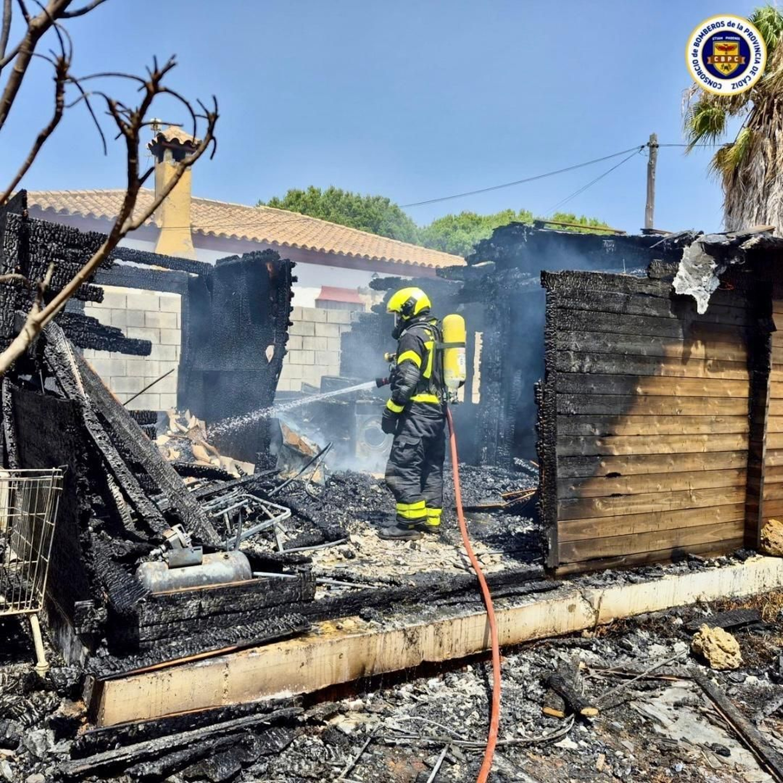 Los bomberos de Chiclana durante la extinción del fuego en una casa de madera en la zona del Pinar de los franceses.