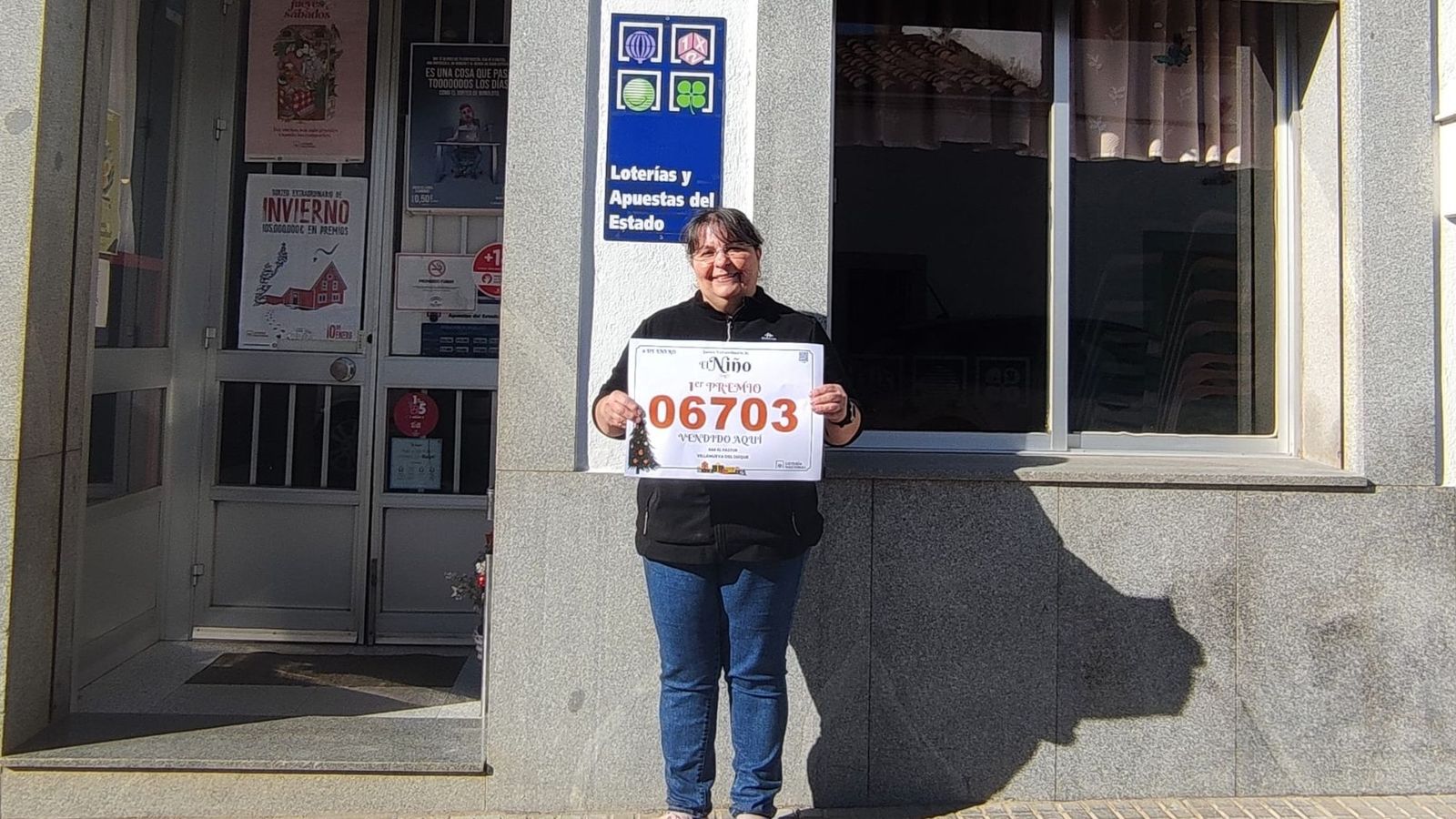 Carmen Gómez muestra el cartel del primer premio del Sorteo del Niño.