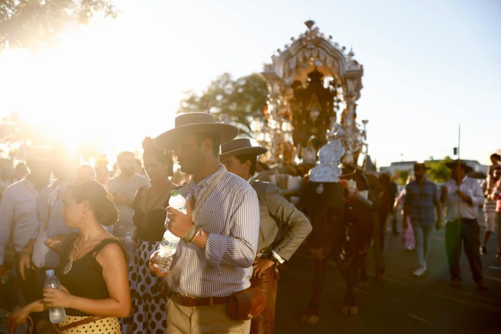 Peregrinos de la Macarena con botellas de agua tras una tarde a 40 grados.