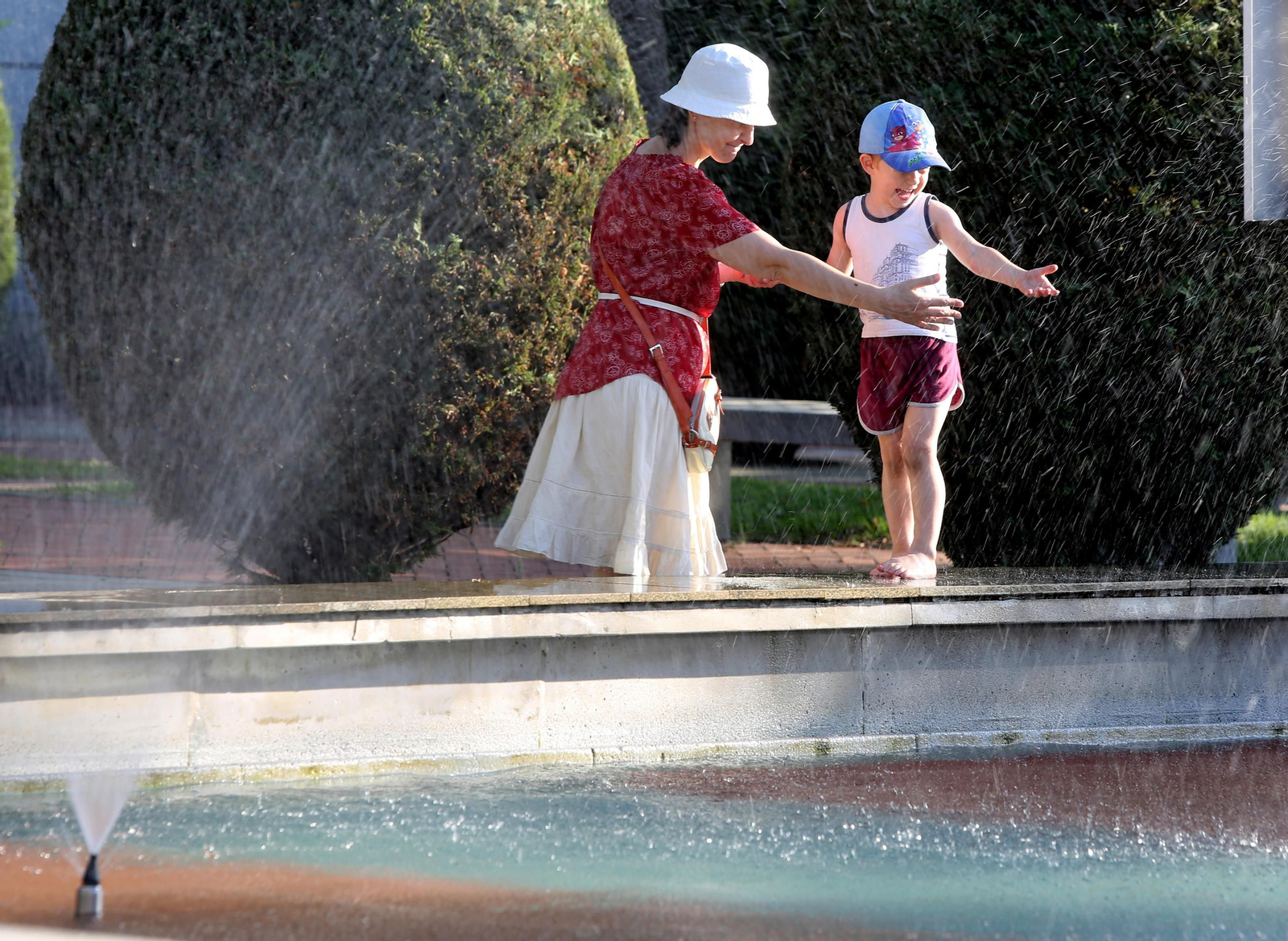 Una mujer y un niño juegan en la fuente. Una mujer y un niño juegan en la fuente.