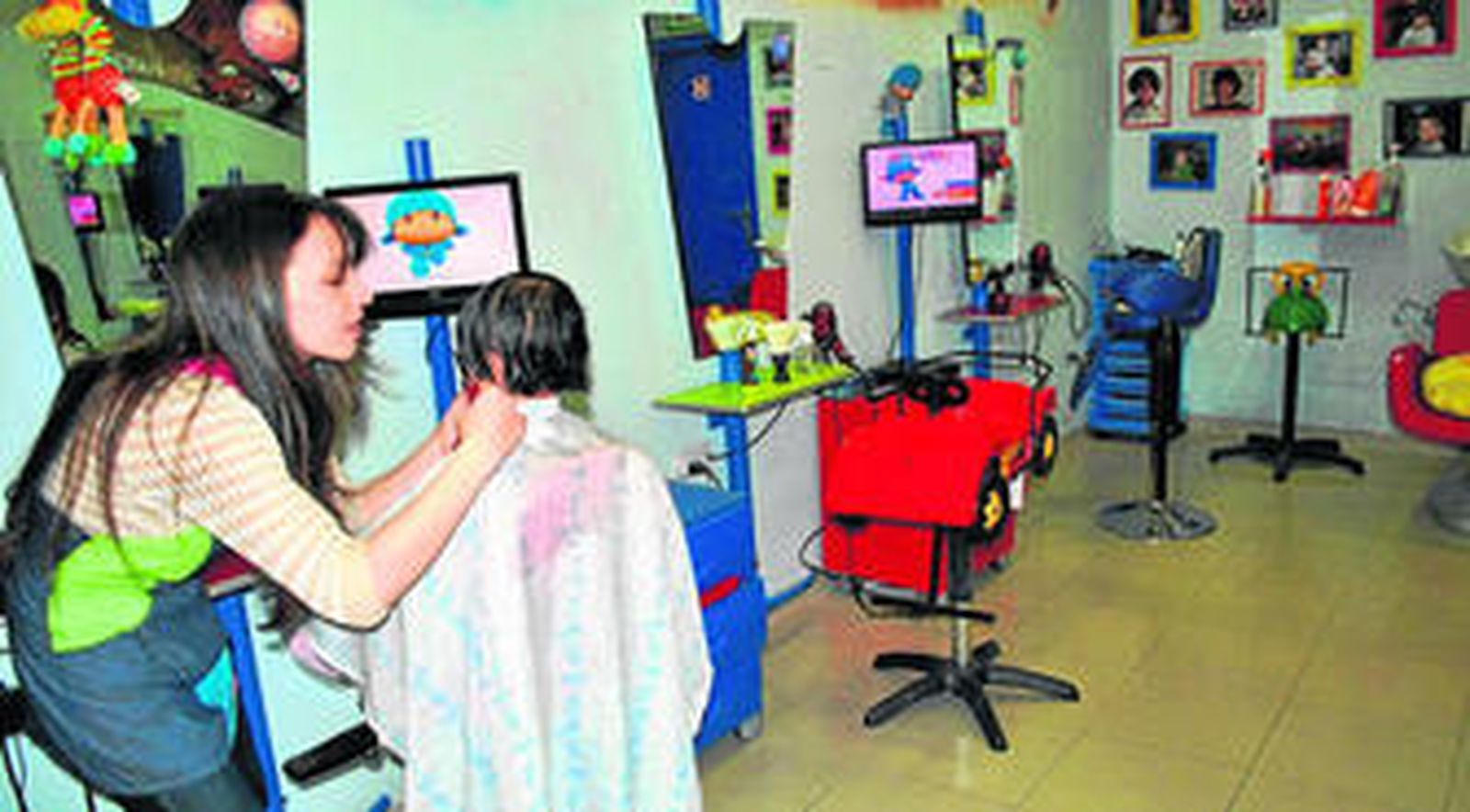 Lorena Villarmosa pela a un niño en su peculiar peluquería infantil.