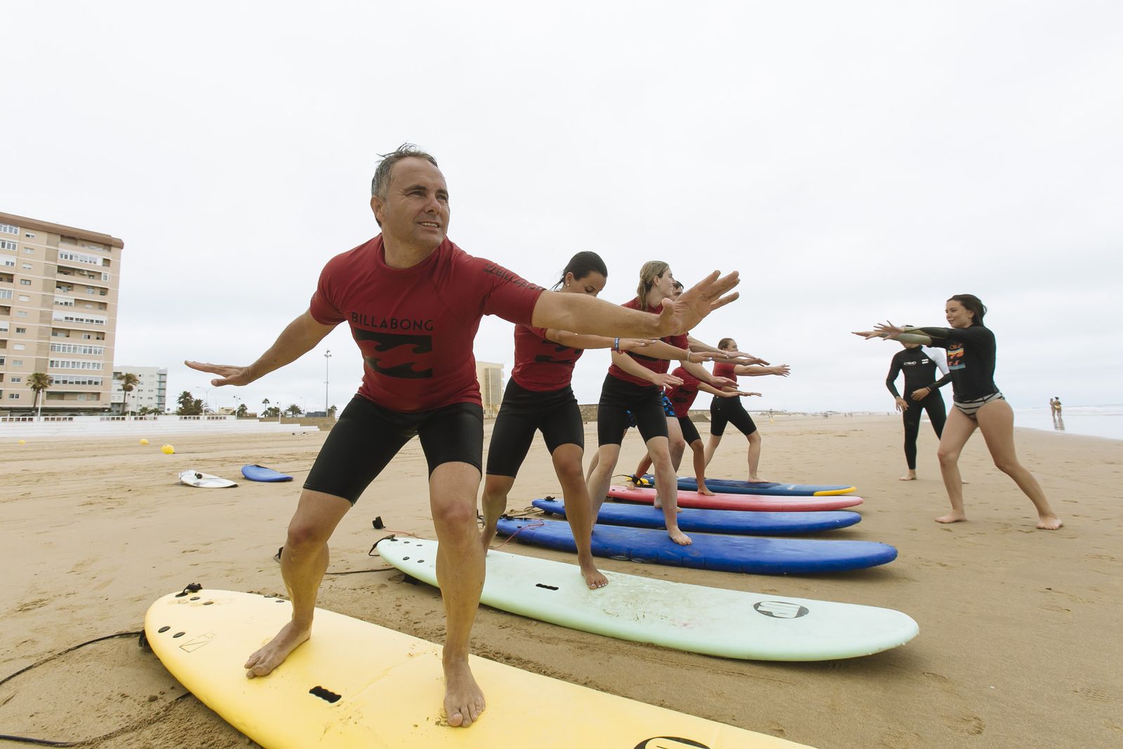 Instructores de la escuela Cádiz Surf Center con un grupo de alumnos extranjeros este lunes en la playa Victoria.