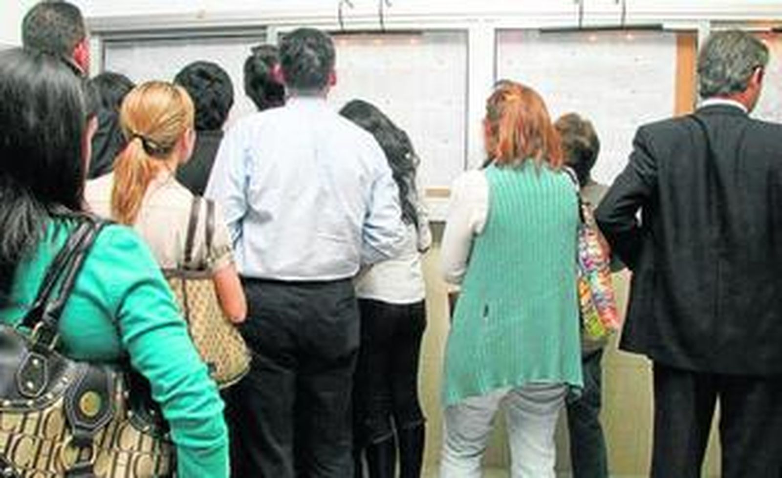 Un grupo de padres mira los listados de admisión en un proceso anterior.