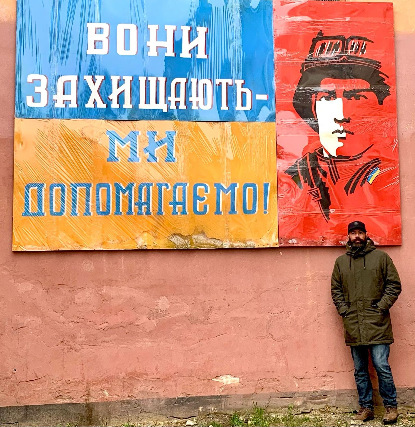 Jaime Fernández Ortiz junto a un cartel situado en una escuela de Komarno, que significa: "Ellos protegen, nosotros ayudamos"