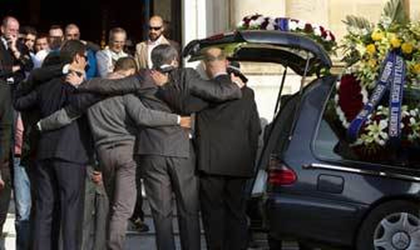 Familiares y amigos de Gustavo Virués, junto al coche fúnebre en el que viajaban sus restos mortales, ayer. /Román Ríos