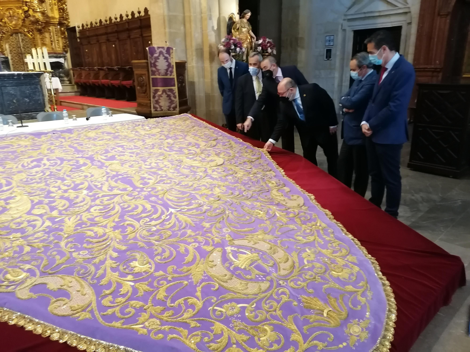 José Manuel Maqueda, hermano mayor, y los participantes en la mesa redonda observan la restauración del manto.