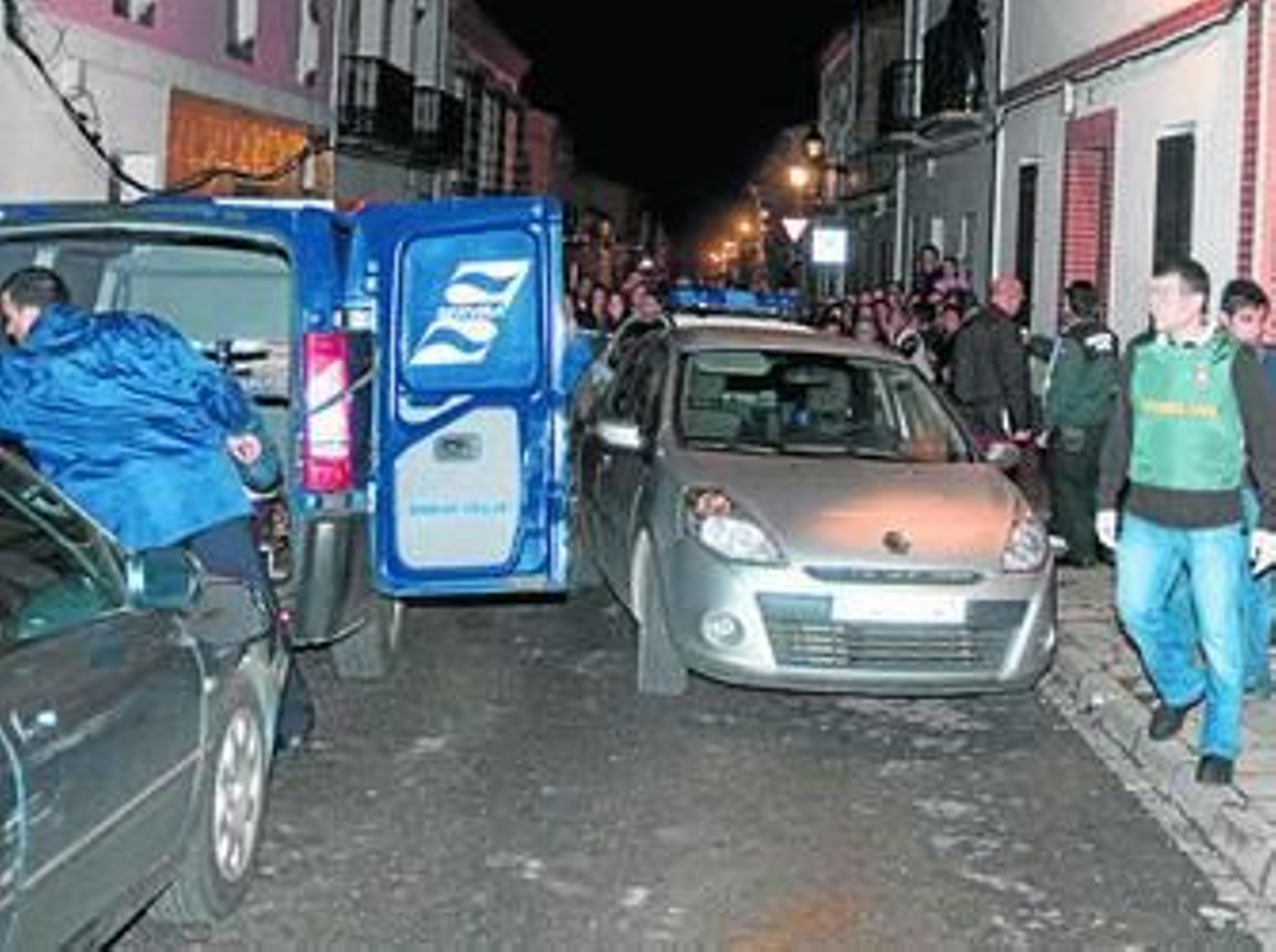 Un agente de la Guardia Civil y el furgón funerario en la vivienda de Pilas donde fue hallado el cuerpo.