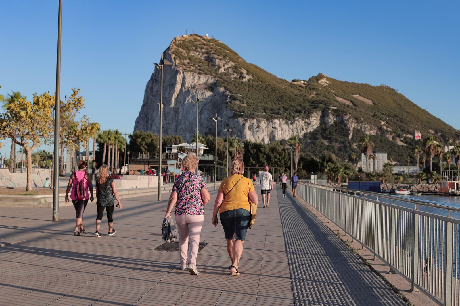 Varias personas caminan por el  paseo marítimo de La Línea