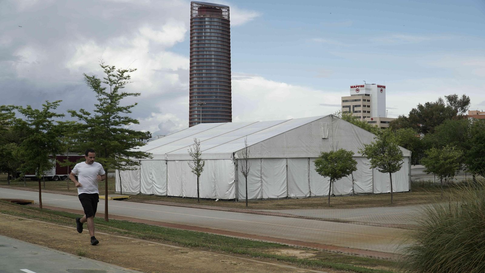 Un corredor pasa junto a una de las carpas, con el rascacielos al fondo.