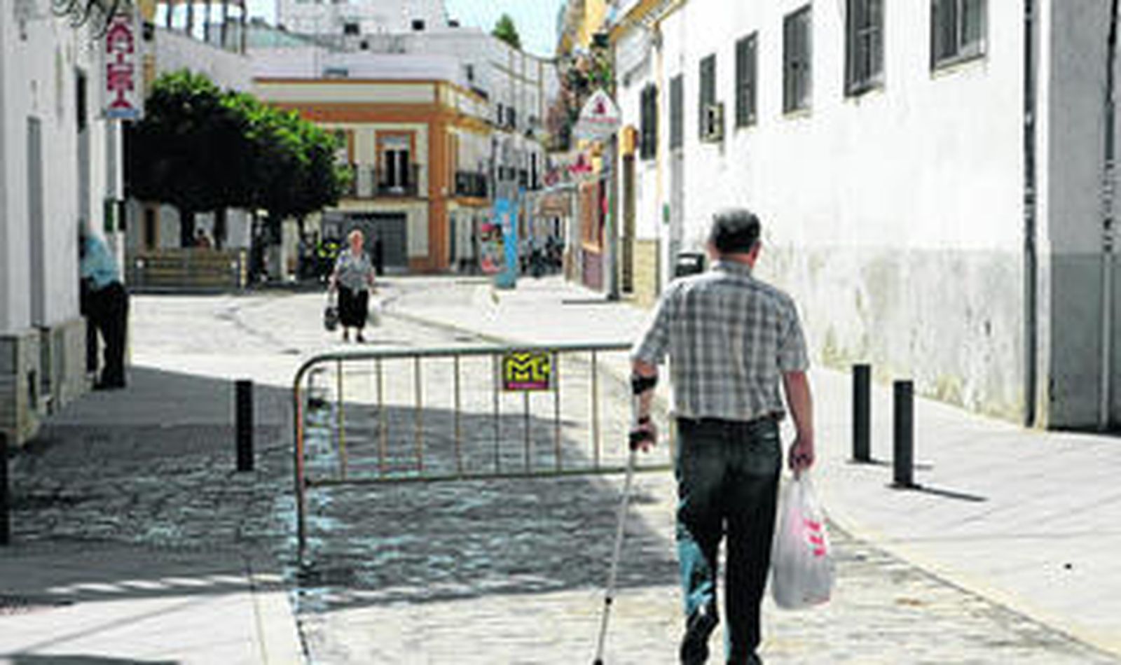 Dos vecinos cruzan por la calle Alfarería de Triana, donde Emasesa ha mejorado las redes de saneamiento, además de reurbanizarla.