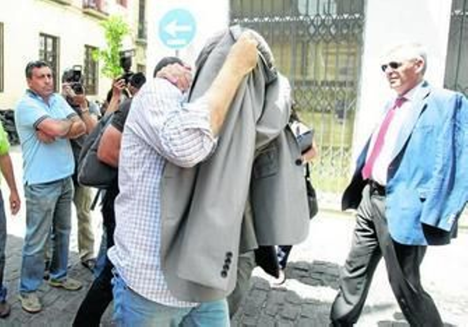 Domingo Enrique Castaño cubre su rostro con una chaqueta durante uno de los registros, en presencia de su abogado, José Manuel García-Quílez.