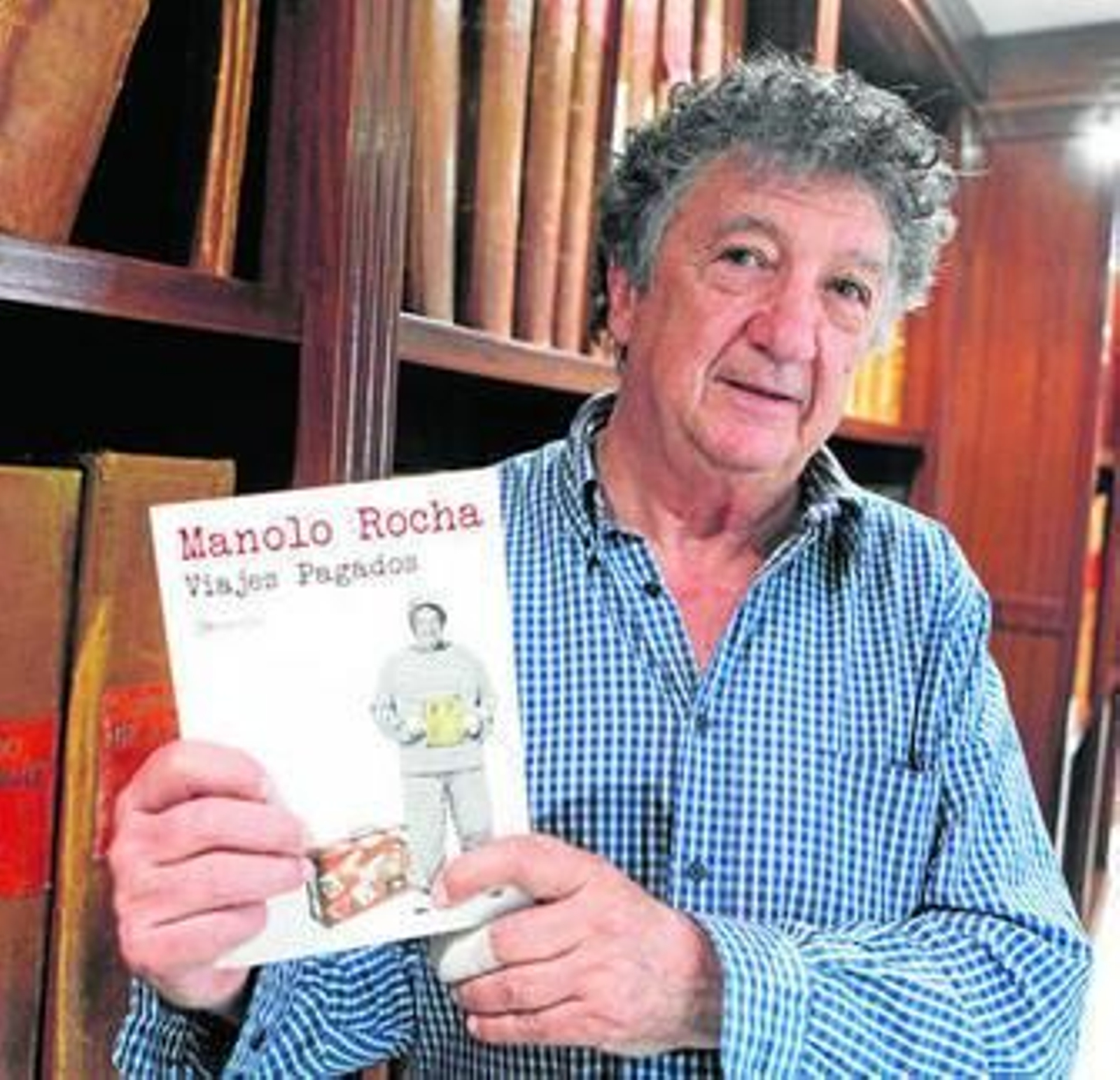 Manolo Rocha muestra un ejemplar de su libro 'Viajes pagados' en la hemeroteca del Diario.
