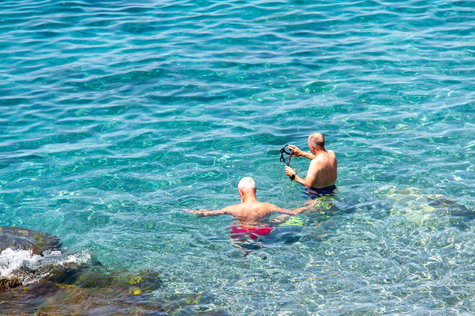 Dos personas disfrutan de la playa de La Herradura antes de hacer esnórquel