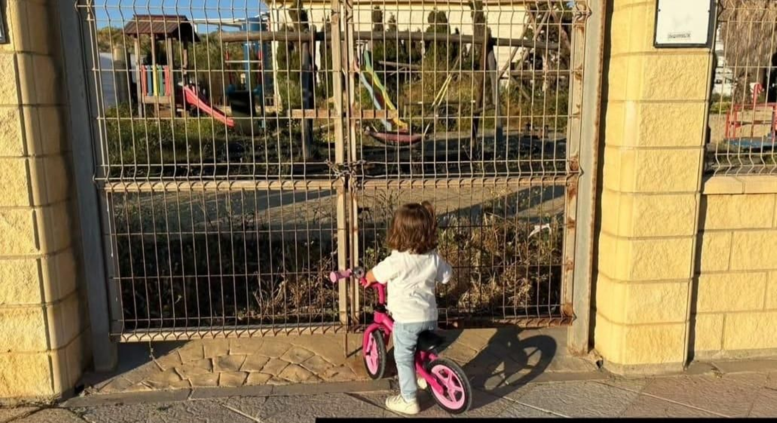 Una niña ante las puertas cerradas del parque infantil del paseo marítimo de Tarifa.
