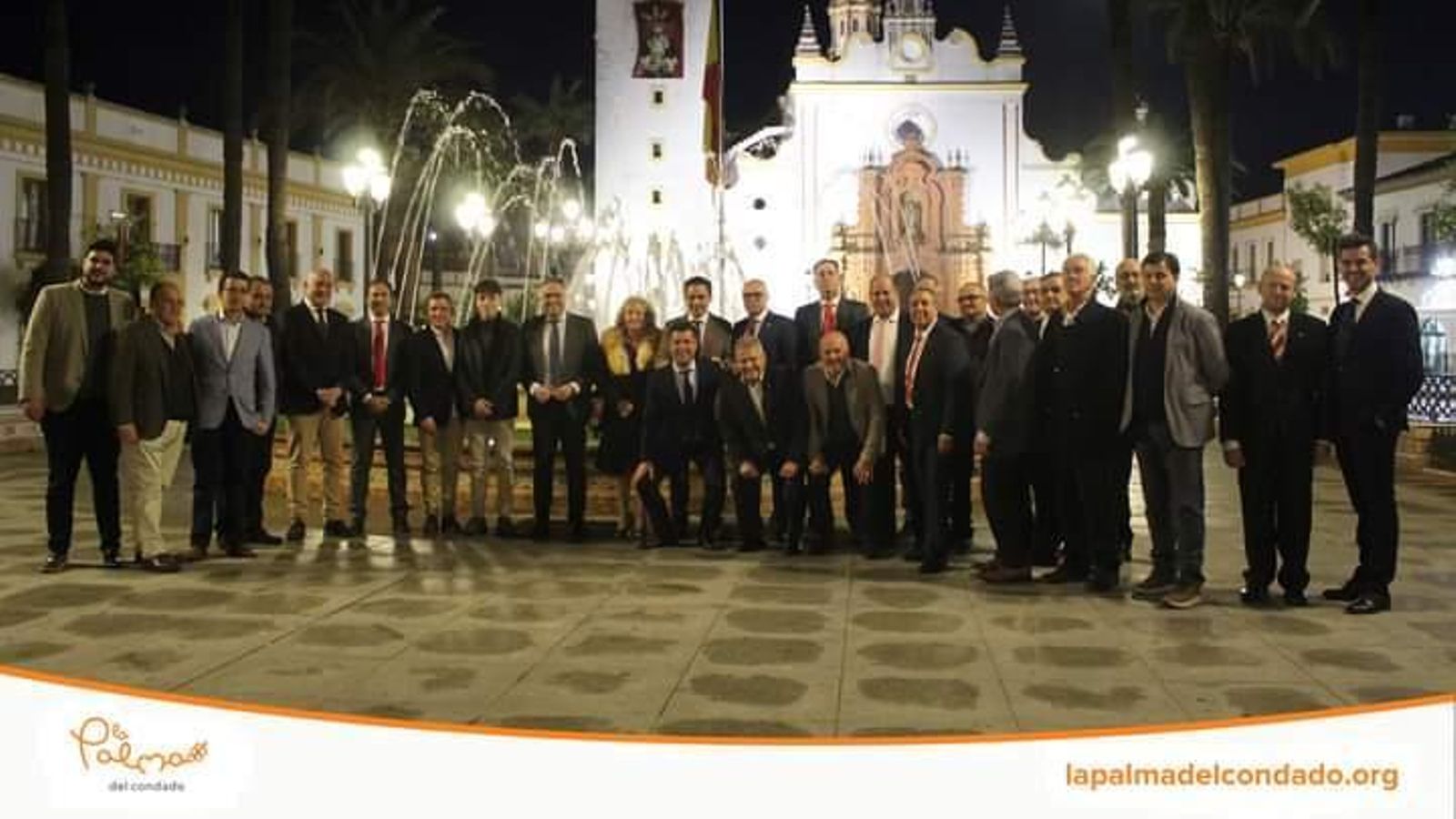 La viuda de Pedro Berruezo posa con los peñistas y Del Nido Carrasco n la Plaza de España de La Palma del Condado.