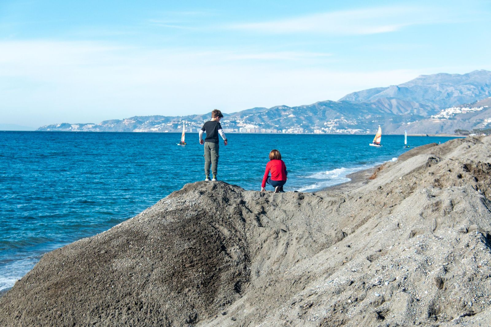 Dos niños juegan en los montículos de arena de Playa Granada
