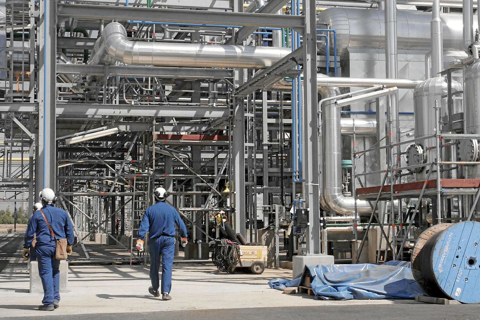 Dos operarios caminan dentro de una factoría de Huelva.