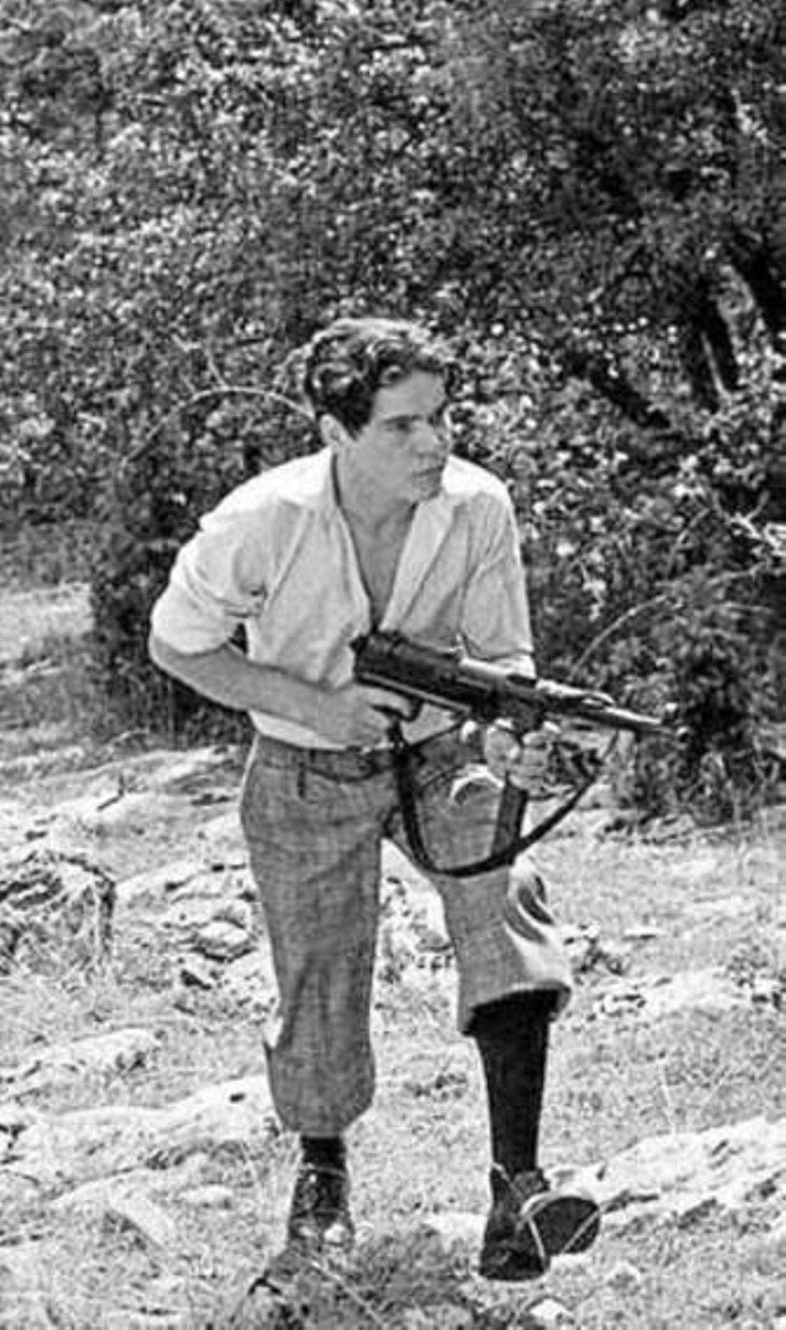 Pierre Blaise (Lucien) metralleta en mano por las afueras del pueblo.