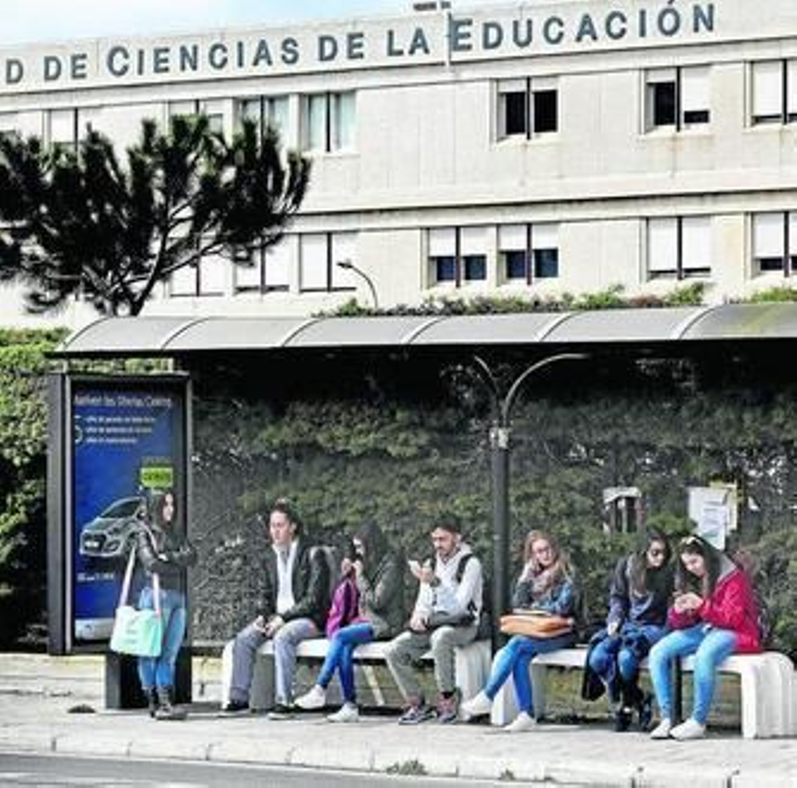 Alumnos esperando el autobús ante la Facultad de Ciencias de la Educación.