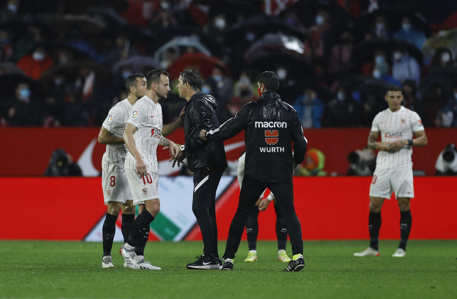 Julen Lopetegui habla con Joan Jordán ante Rakitic bajo el aguacero del Sevilla-Barcelona.