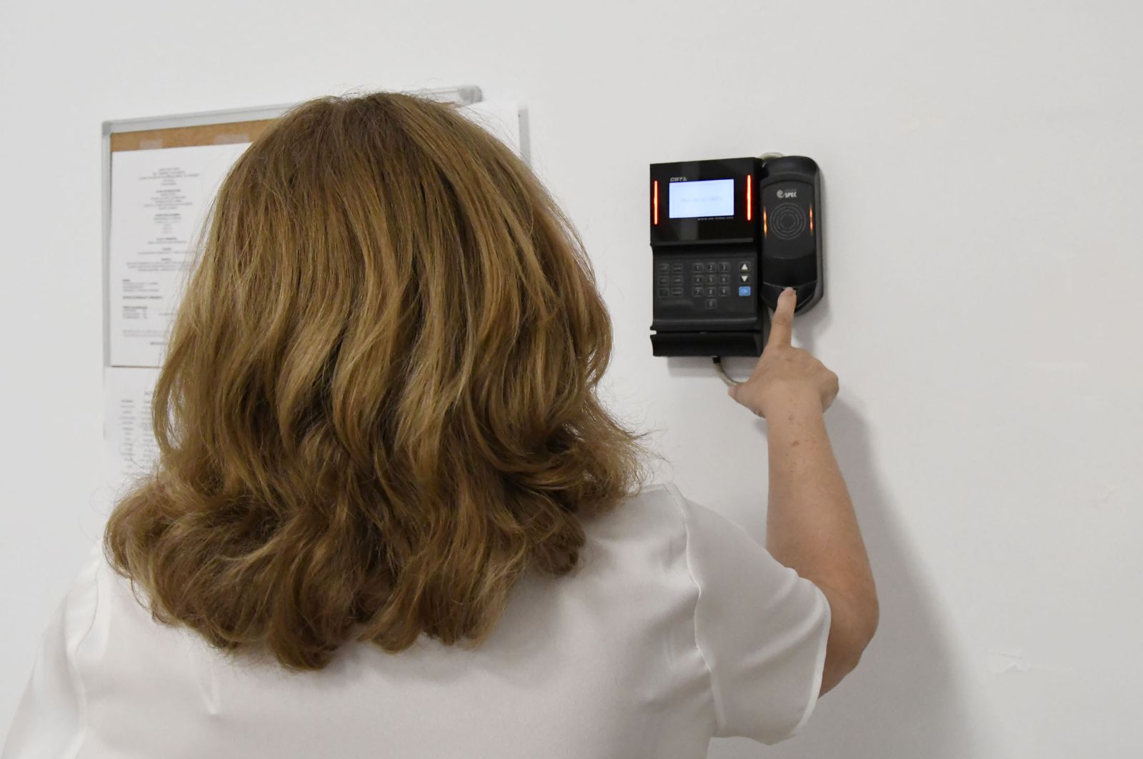 Una trabajadora emplea el sistema digital de huella para acceder a su puesto.