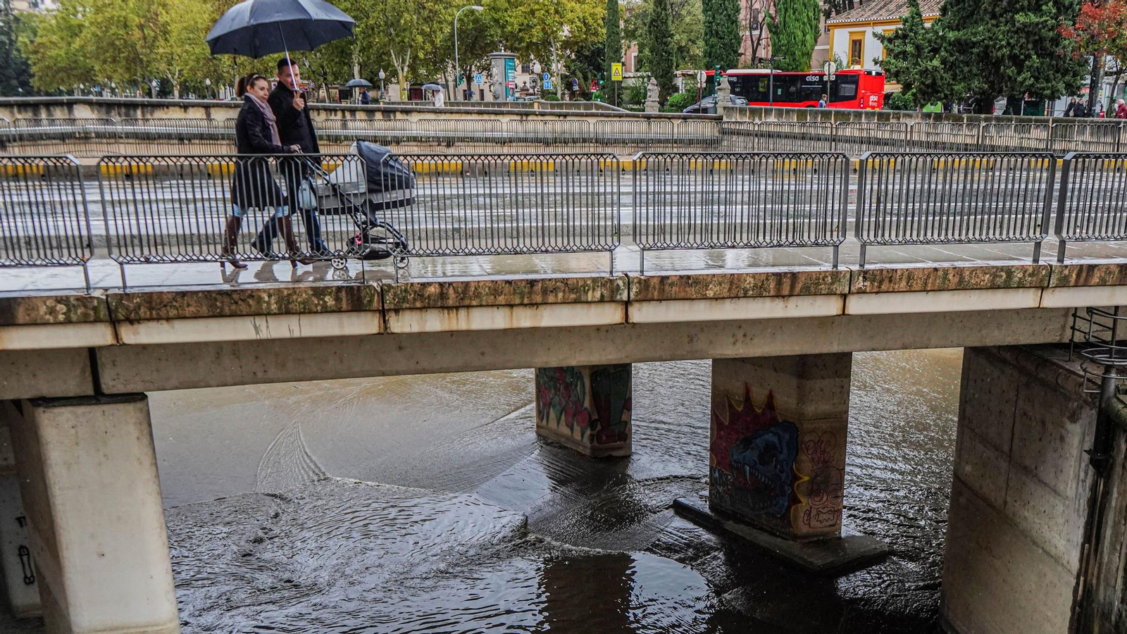 Un matrimonio pasa con un carrito de bebé sobre el Río Genil en Granada Un matrimonio pasa con un carrito de bebé sobre el Río Genil en Granada