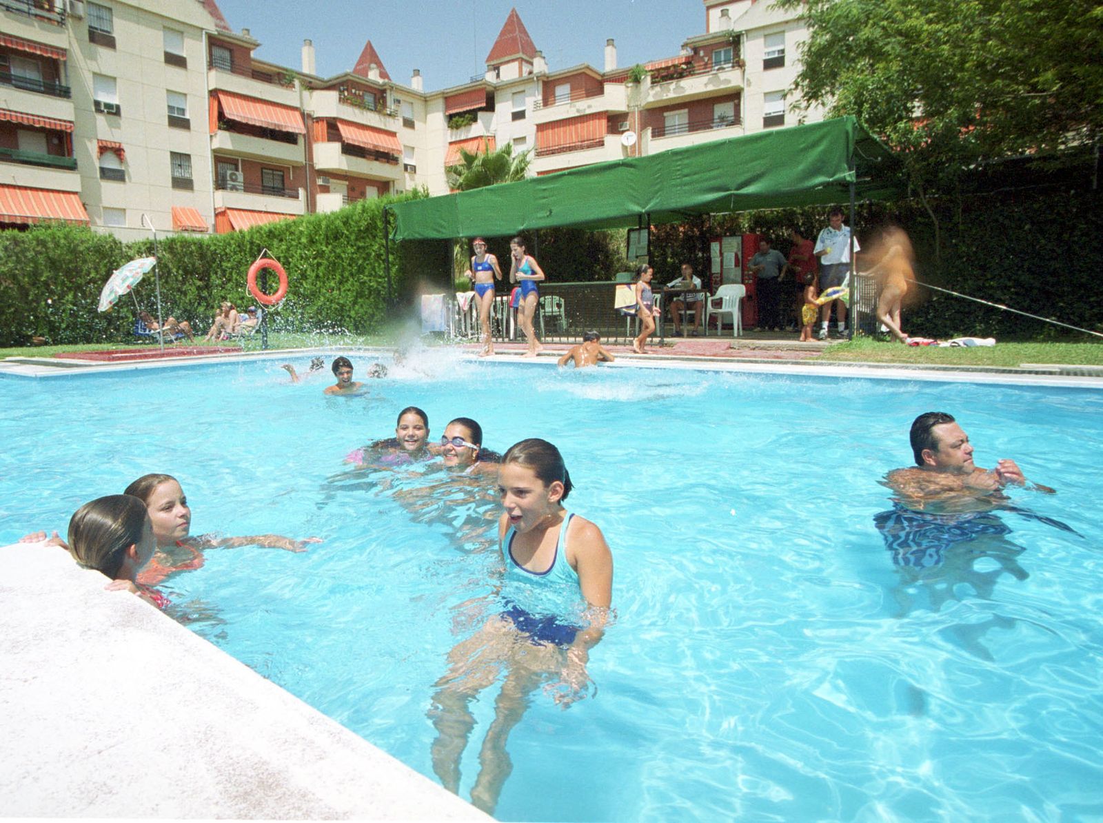 Unos jóvenes disfrutan en la piscina comunitaria.