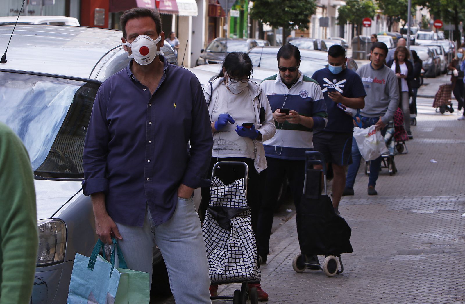 Varias personas hacen cola a las puertas de un establecimiento alimenticio.