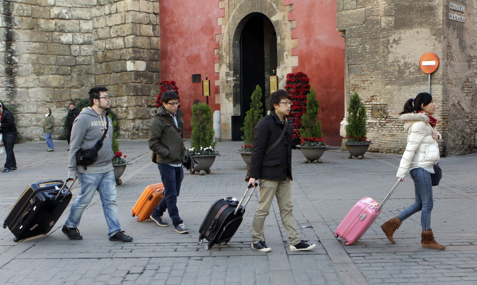 Un grupo de turistas, maleta en mano, pasa por delante de la Puerta del León del Real Alcázar.