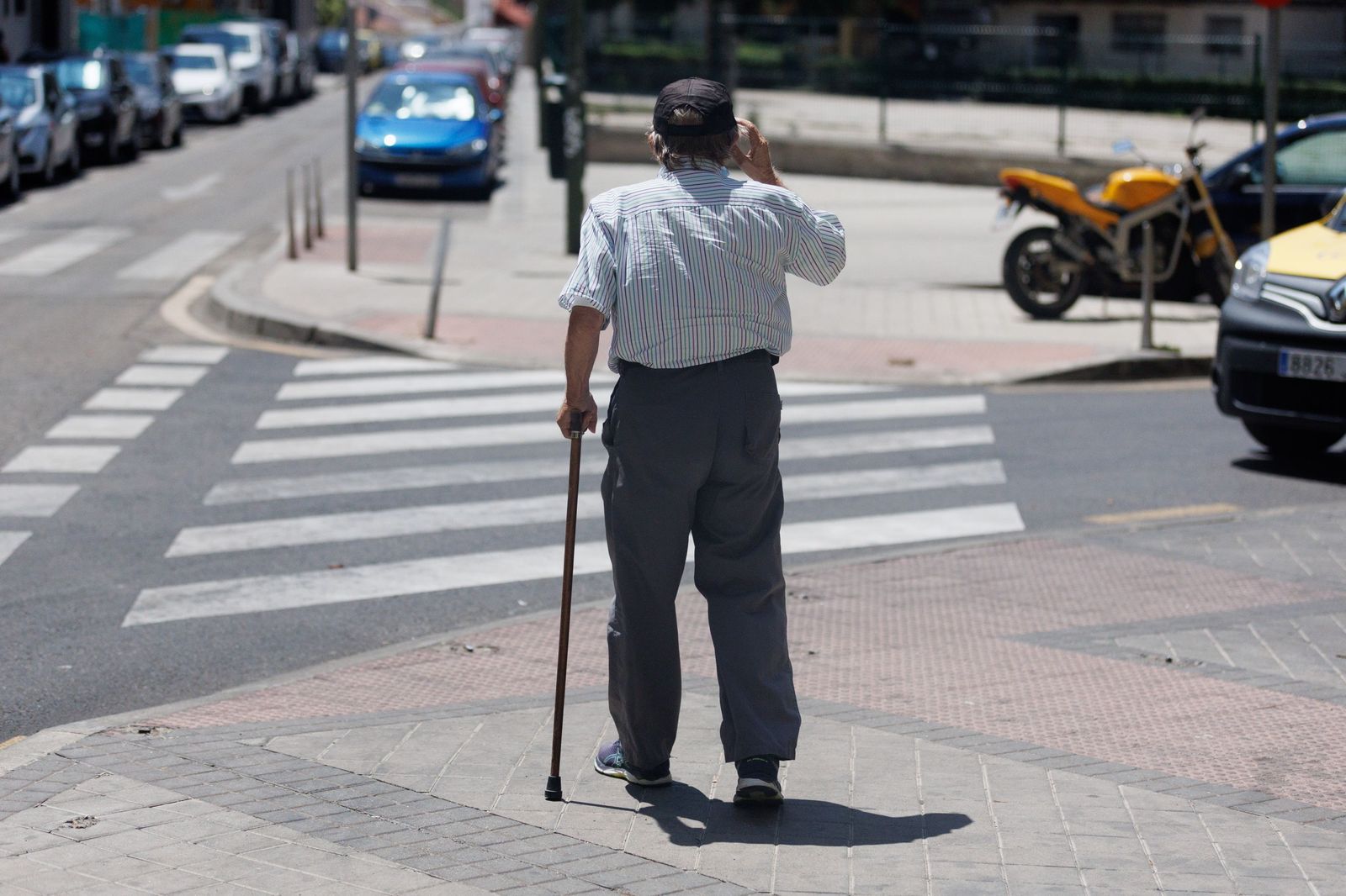 Un anciano se ayuda del bastón para pasear por las calles.