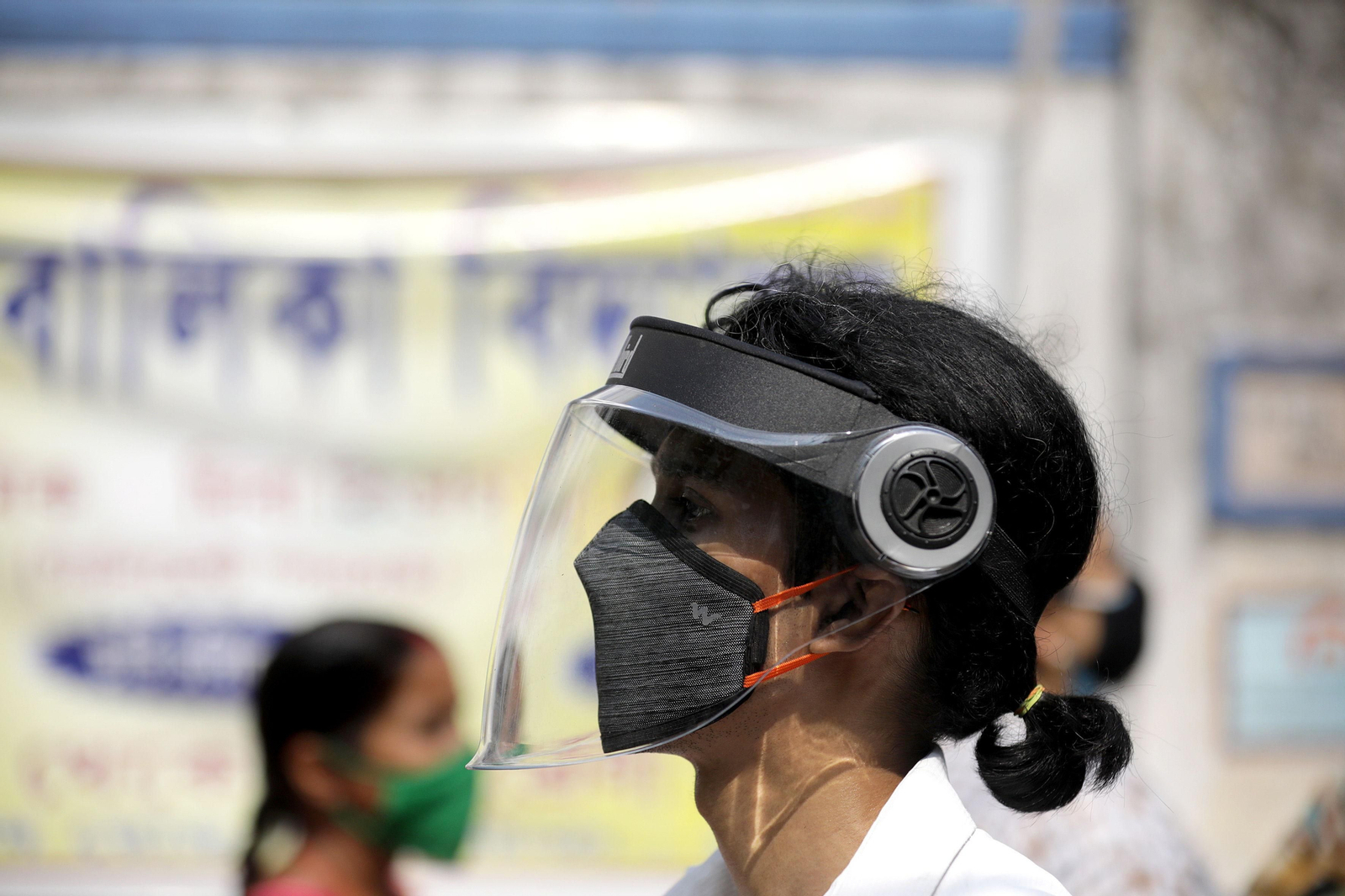 Una trabajadora sanitaria india se protege con mascarilla y pantalla.