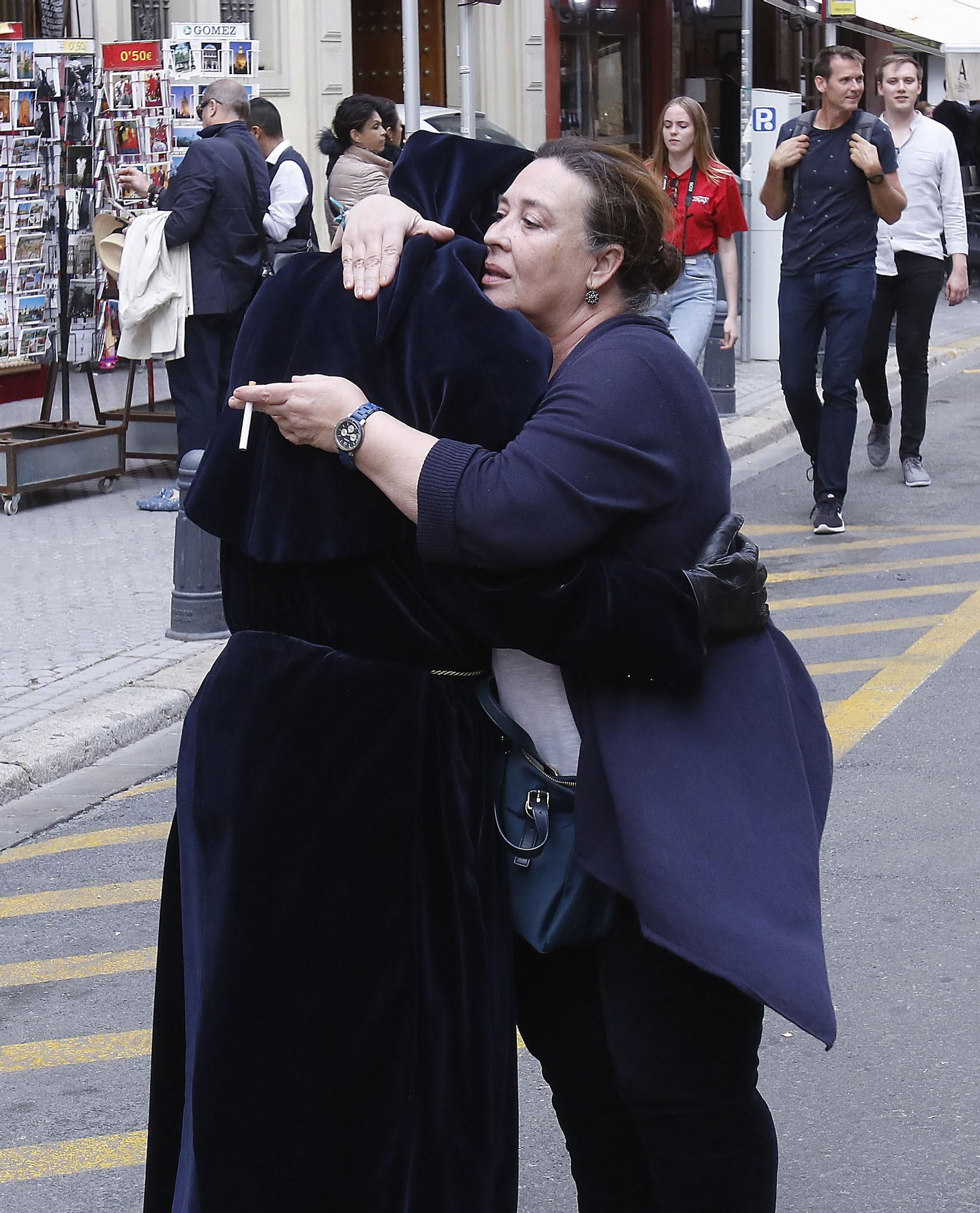 Una mujer consuelo a un nazareno de la Carretería tras no poder realizar la estación de penitencia.