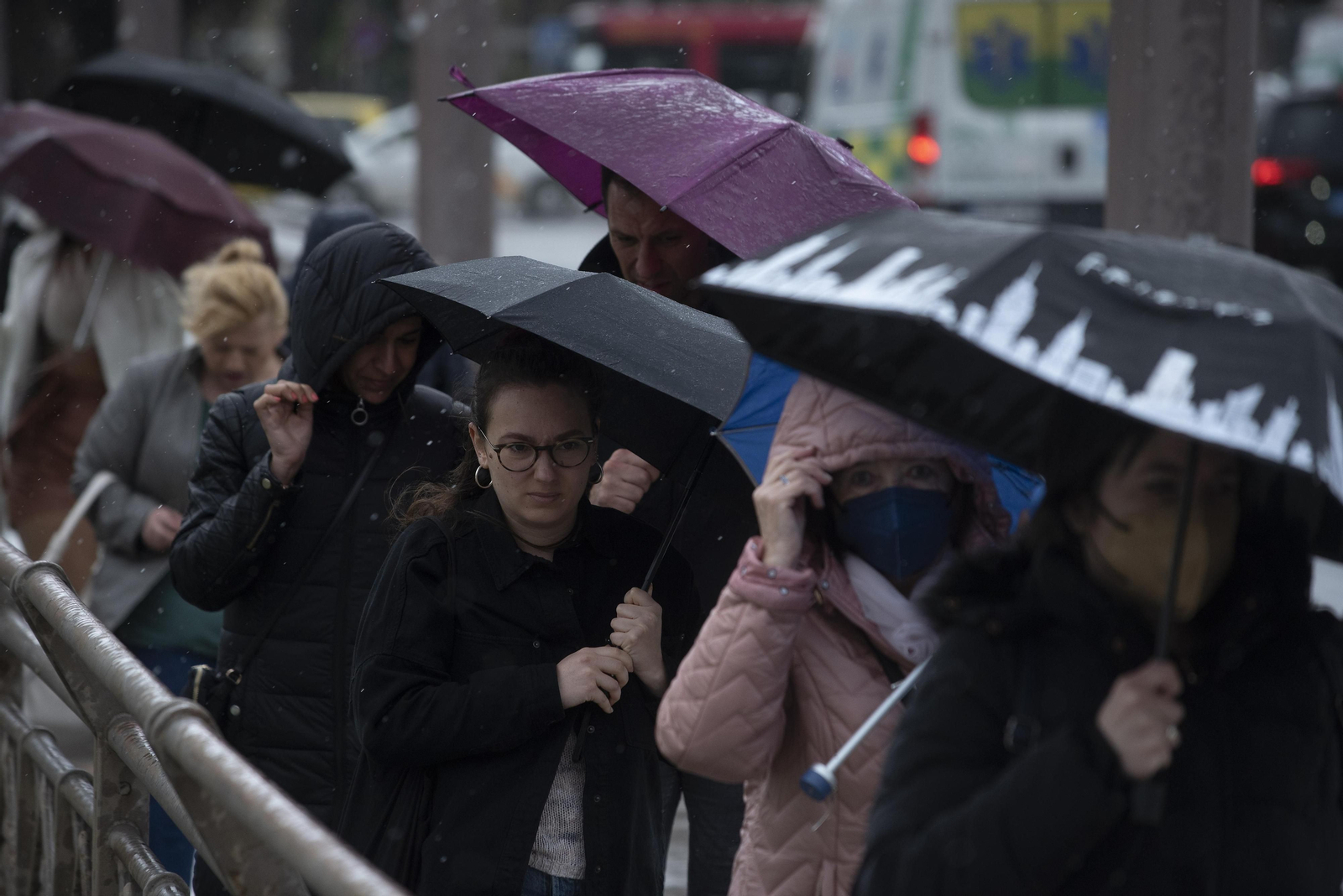 Varias personas se protegen de la lluvia.