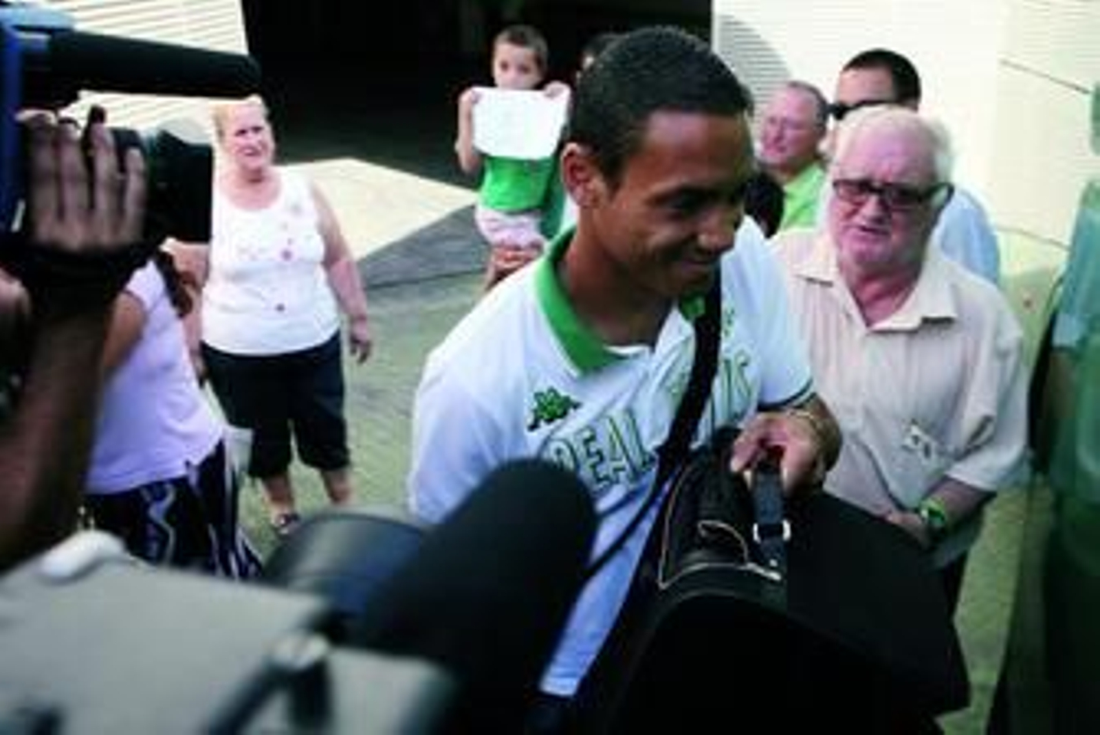 Oliveira, rodeado de aficionados béticos, se dispone a montarse en el autobús.