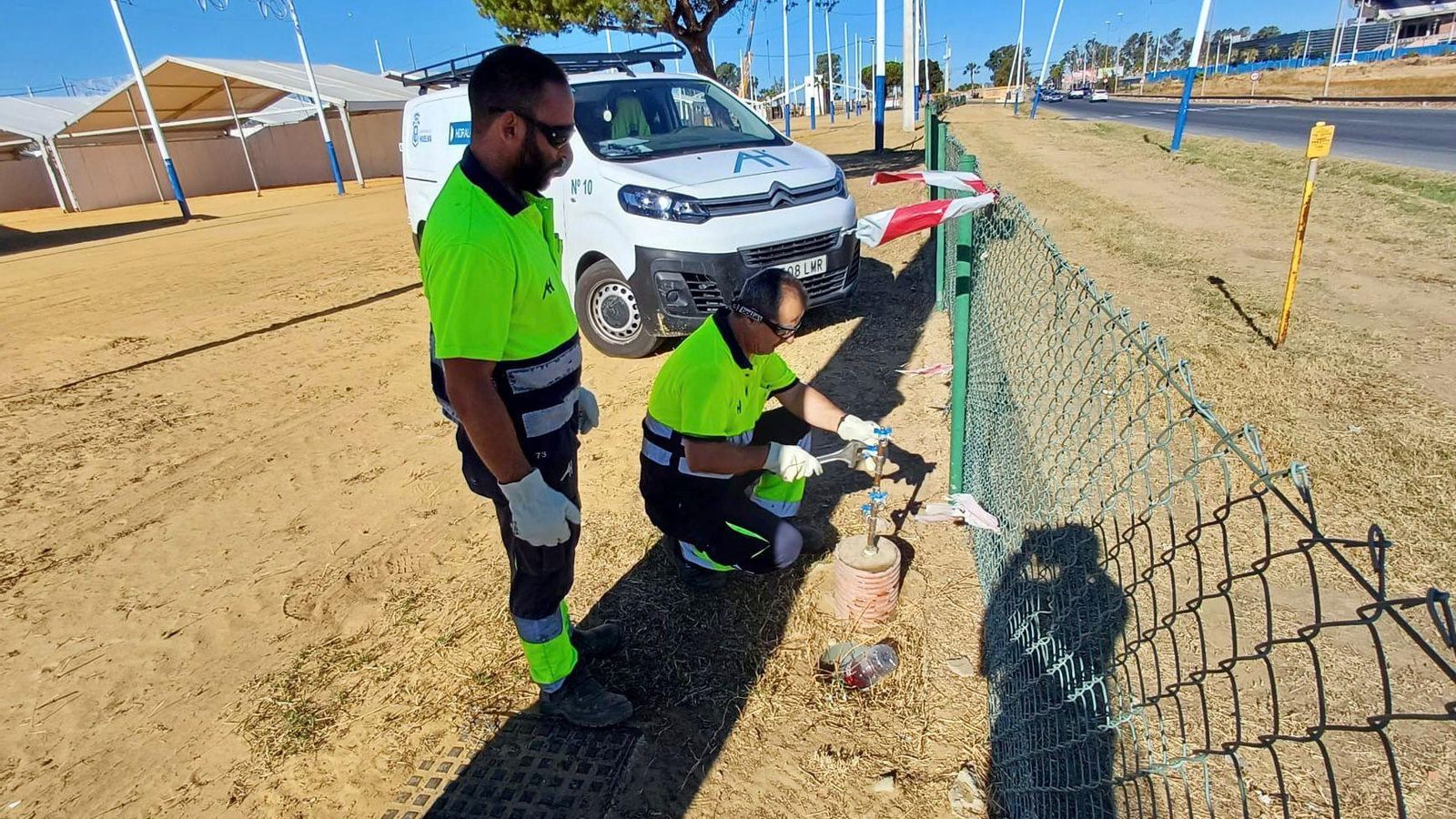 Dos trabajadores de Aguas de Huelva en la puesta a punto del recinto ferial.