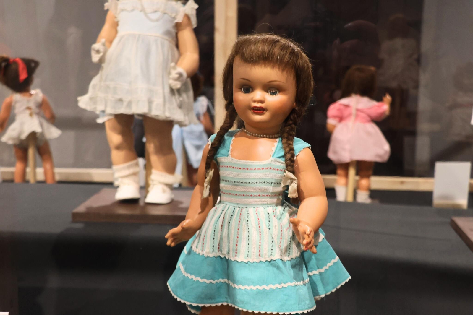 Muñeca de celuloide con trenzas y vestido turquesa, ejemplo del realismo creciente y del cuidado estético en los juguetes infantiles de los años cincuenta.