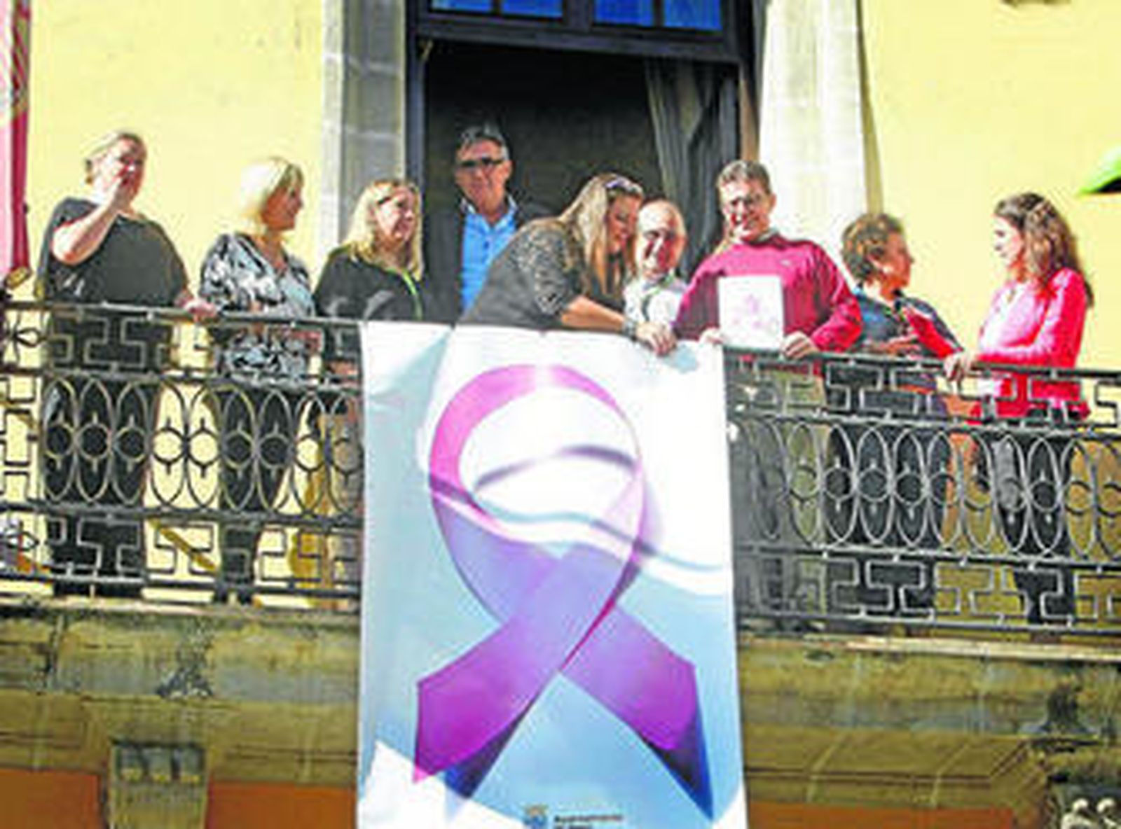 Momento en el que la asociación jerezana y miembros del Ayuntamiento colocan el lazo rosa en el Consistorio.