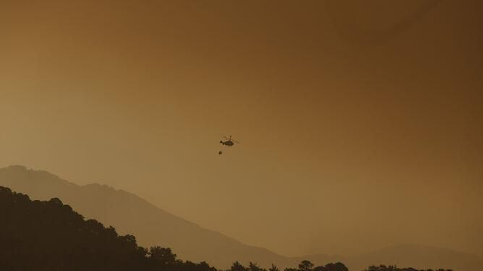 Helicópteros trabajando sobre el incendio al amanecer.