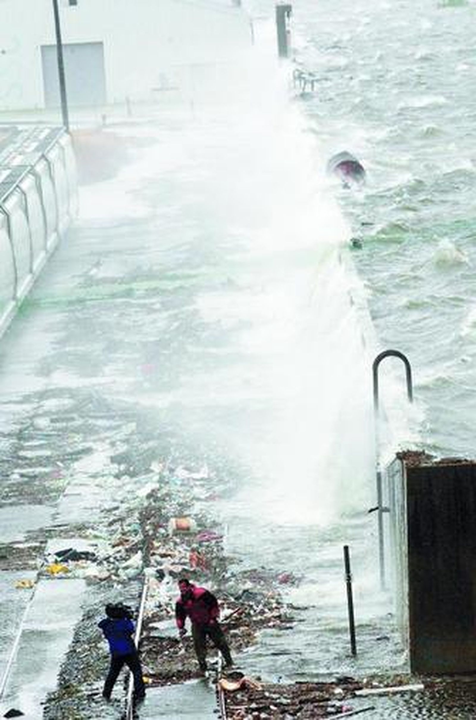 Dos reporteros en una retransmisión, ayer, junto a las olas saltando un dique del Canal Industrial.