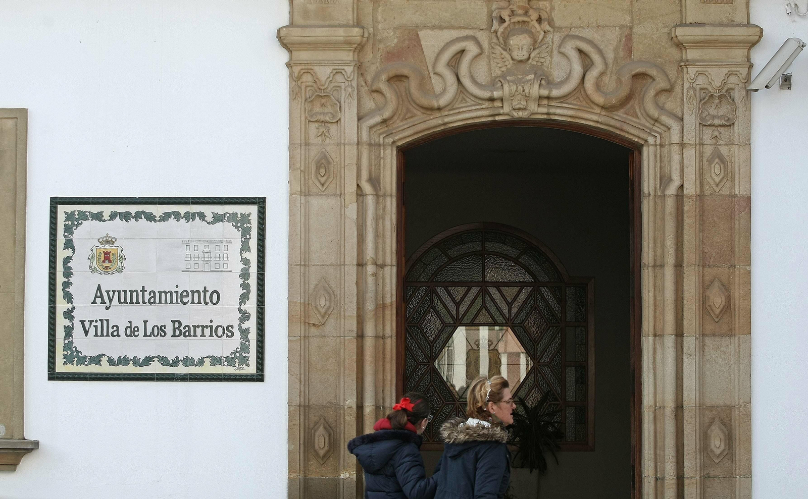 Dos personas pasan por la puerta principal del Ayuntamiento de Los Barrios.