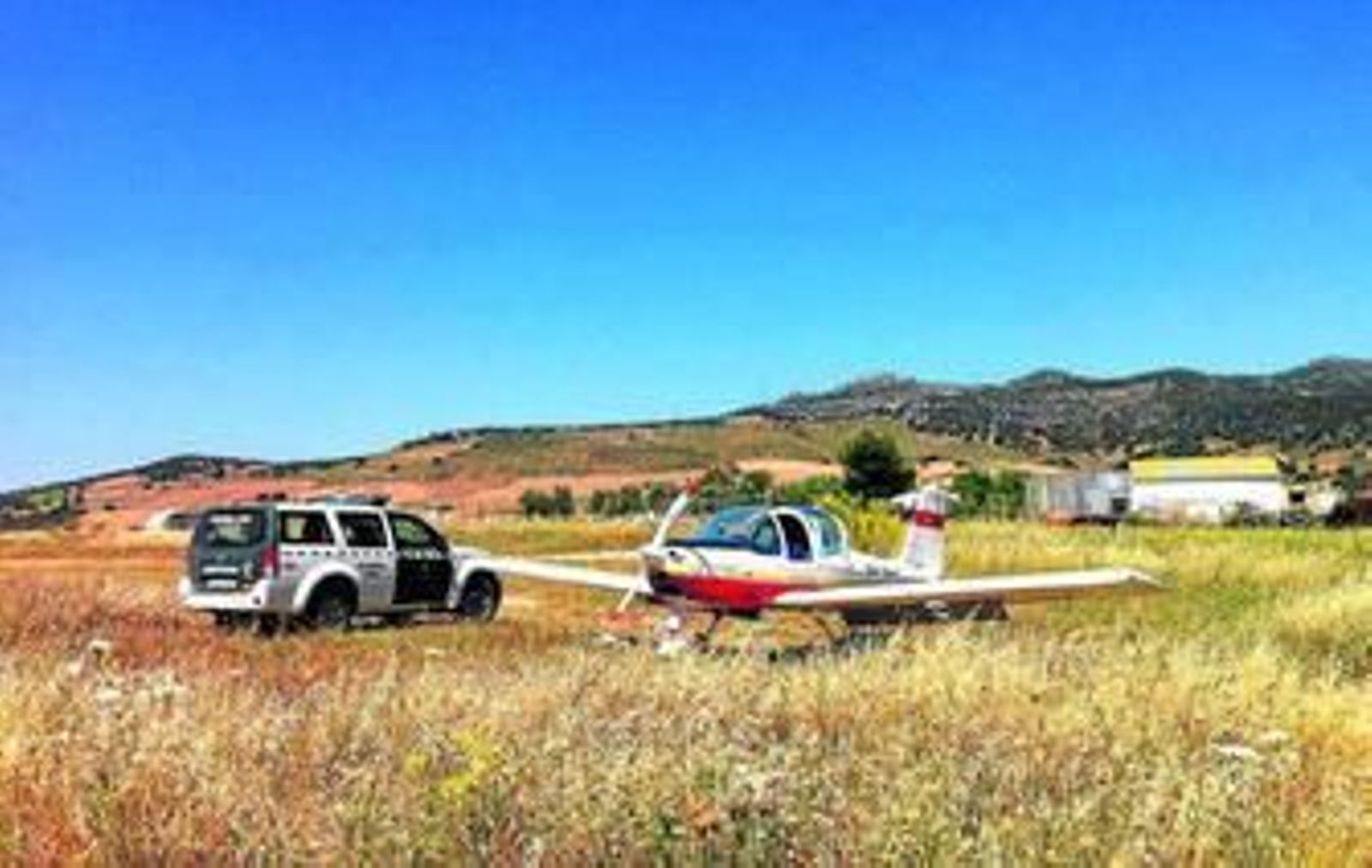 En la imagen, un vehículo de la Guardia Civil junto a la avioneta obligada a aterizar en una pista forestal, en Ronda, anteayer.