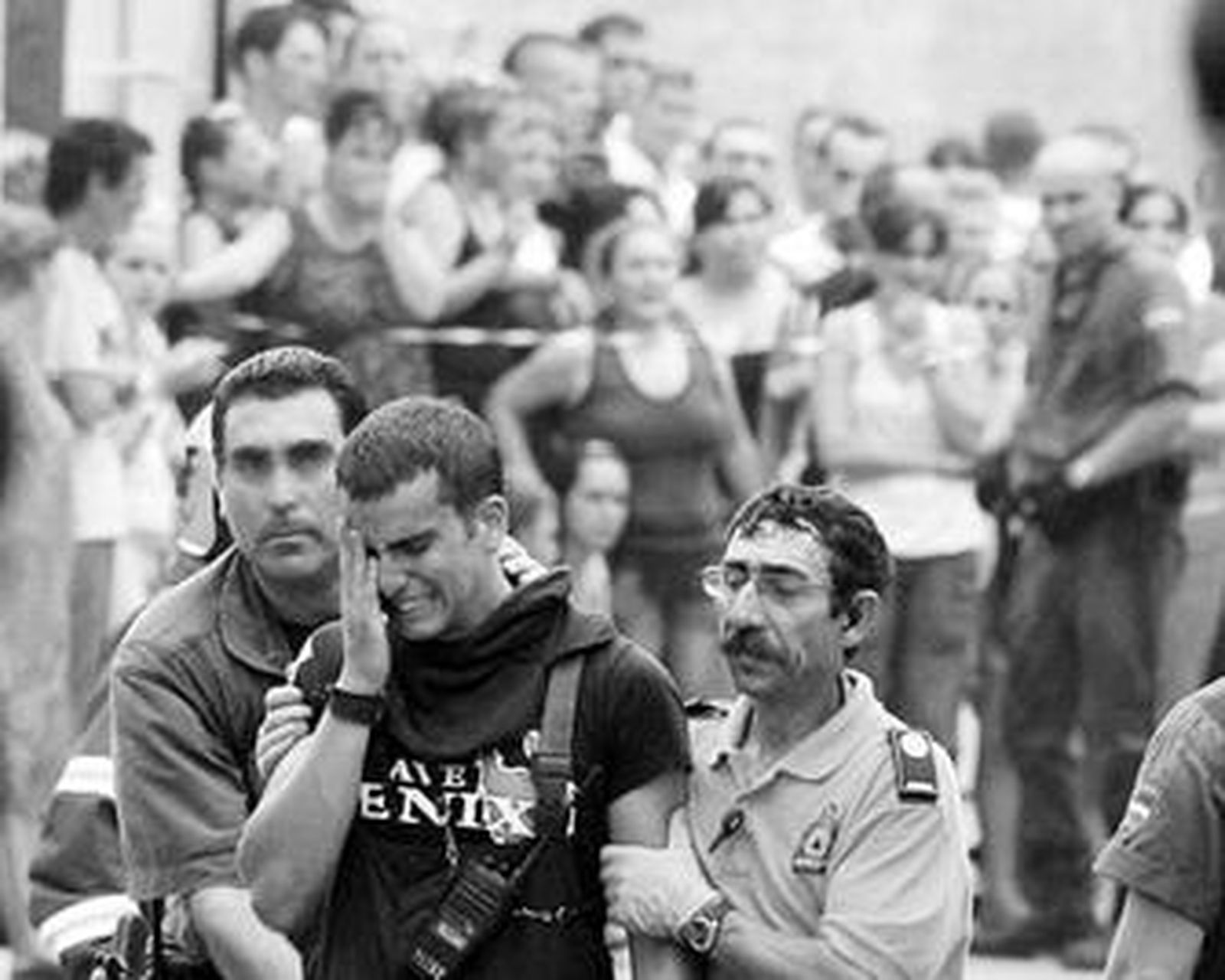 Un bombero no puede contener las lágrimas ante lo ocurrido. Al fondo, los vecinos observan la zona del suceso.