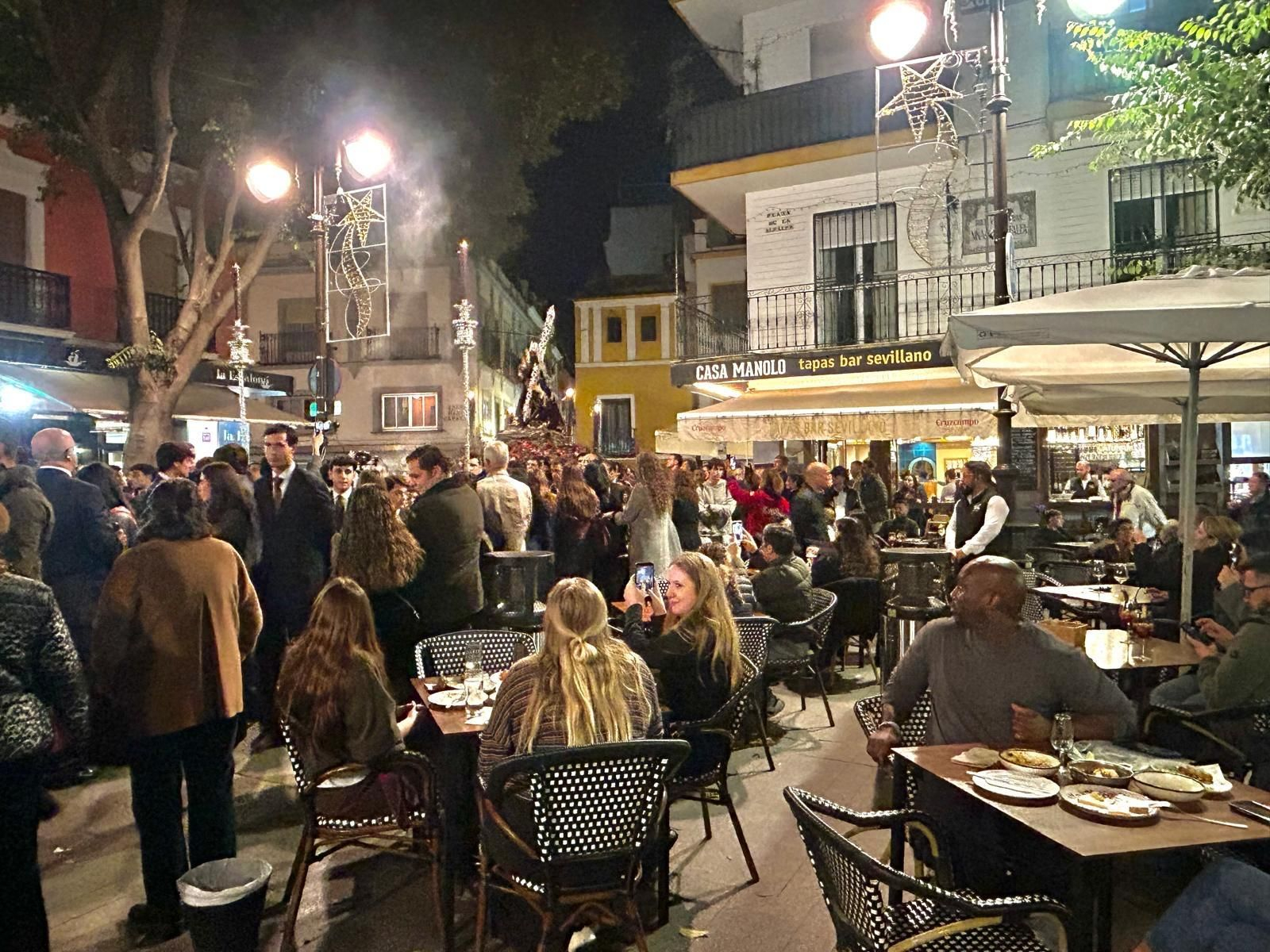 El cliente de un velador de la Alfalfa se vuelve a mirar las andas que portan al Señor de la Penas.