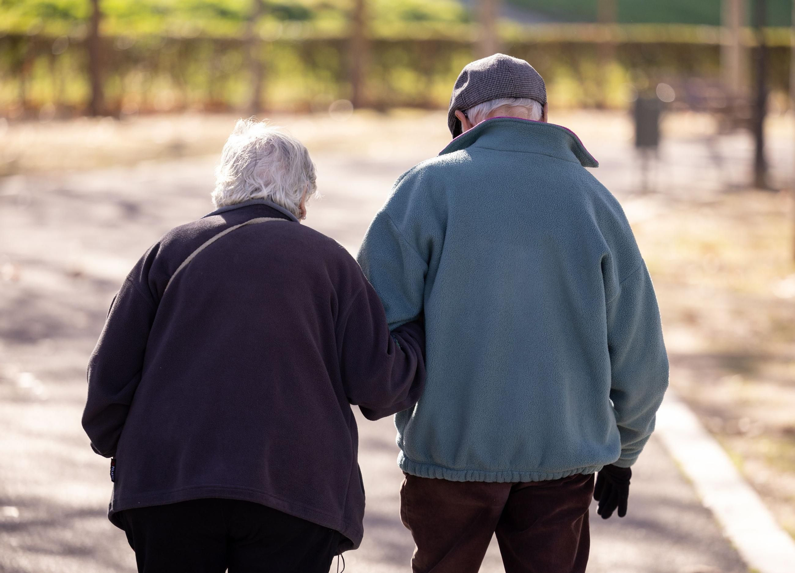 Dos personas mayores caminan por la calle.