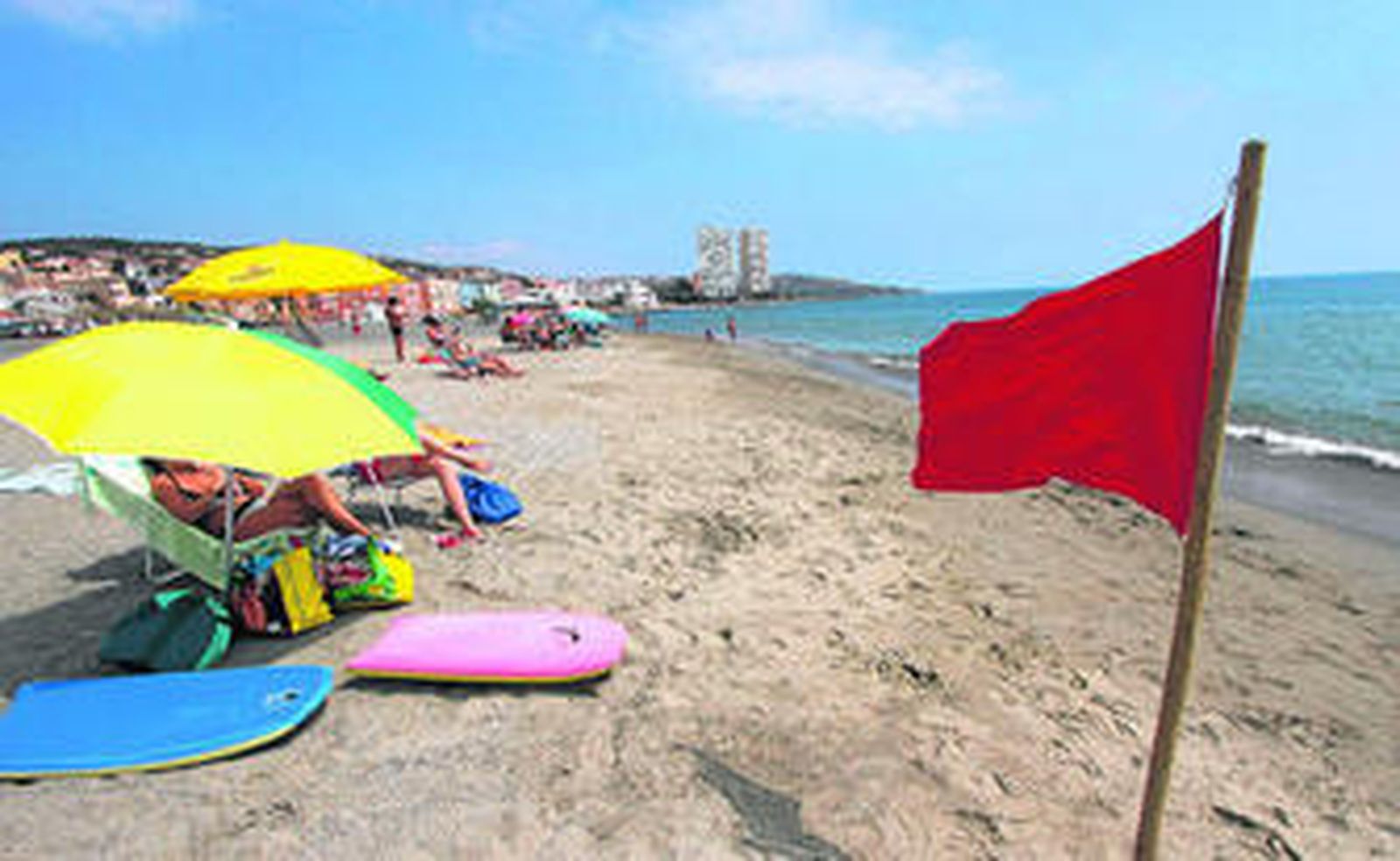 Los bañistas se refugian bajo las sombrillas en la playa de Torreguadiaro durante la prohibición al baño, en la mañana de ayer.