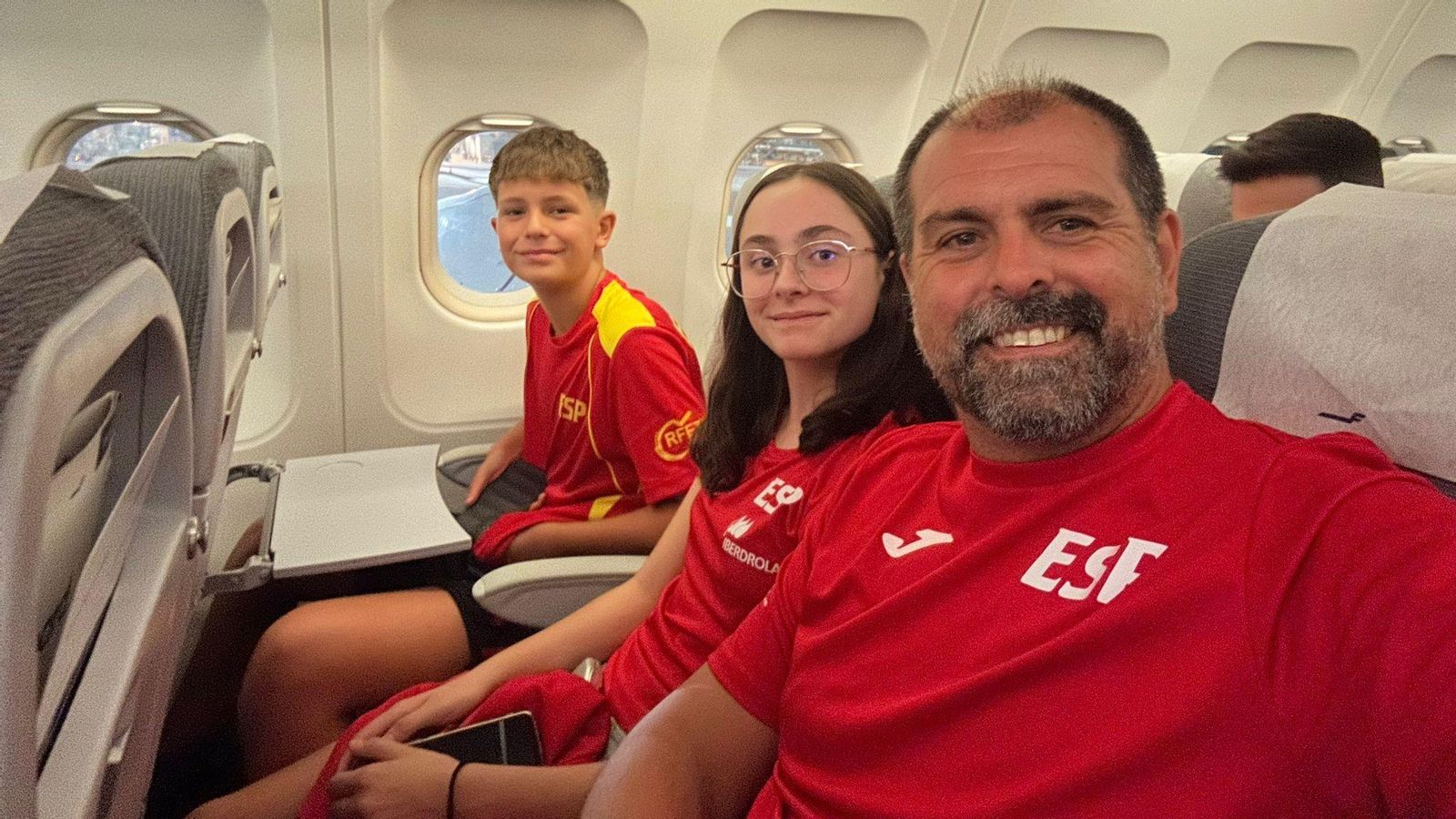 Javier Galán jr., junto a una compañera de selección y a su padre en el vuelo a Letonia.