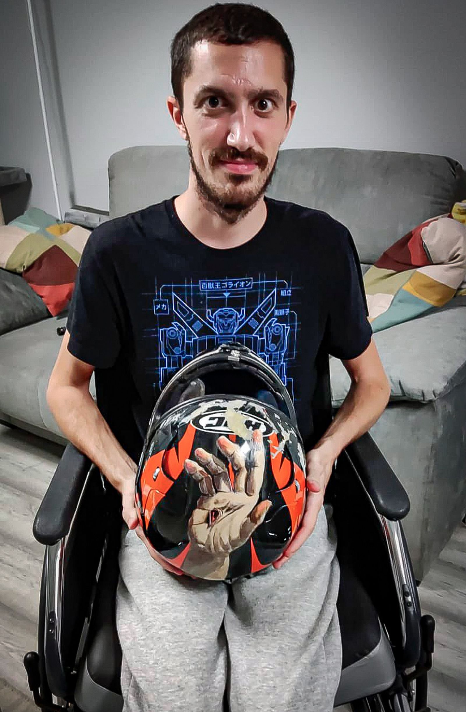 Óscar, en silla de ruedas, sujeta el casco que le salvó la vida