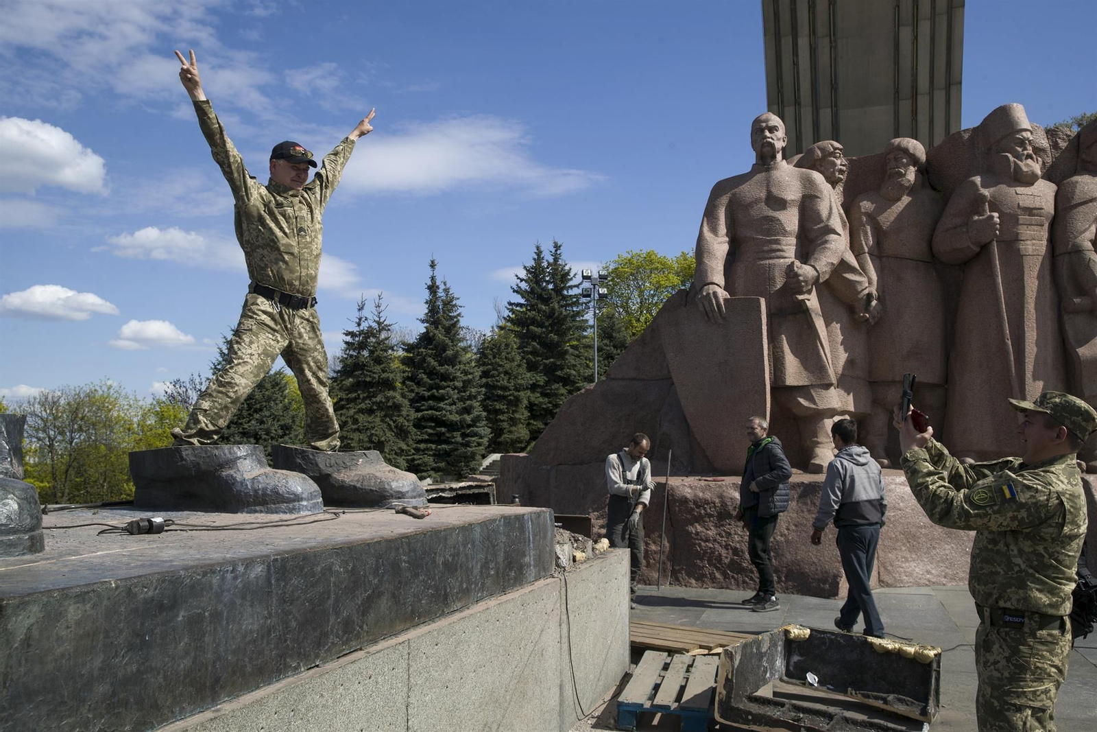 Unos soldados se hacen fotos sobre las últimas piezas de una estatua conmemorativa entre Ucrania y Rusia en Kiev.